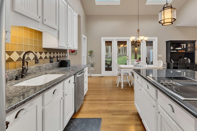 kitchen featuring sink, electric stovetop, dishwasher, white cabinetry, and hanging light fixtures