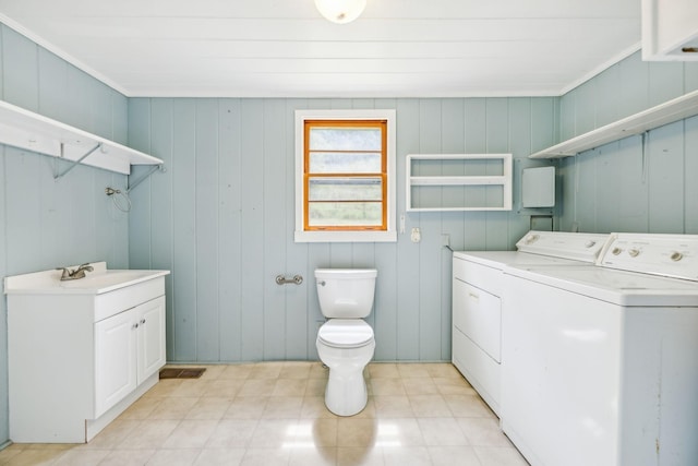 laundry room with separate washer and dryer, wood walls, and sink