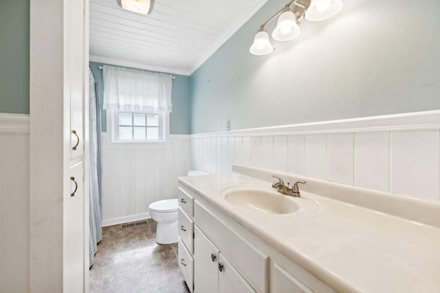 bathroom with toilet, vanity, and ornamental molding