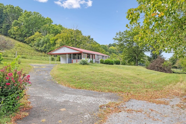 single story home featuring a front yard, a carport, and covered porch