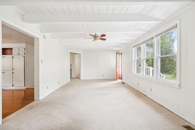 carpeted empty room with beam ceiling and ceiling fan