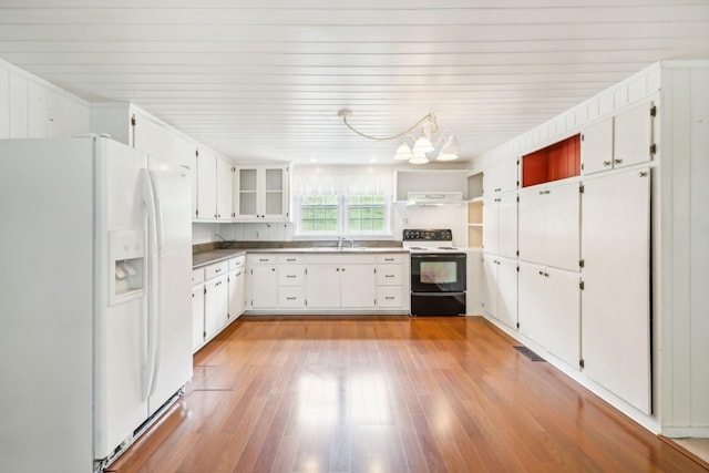 kitchen featuring white appliances, sink, an inviting chandelier, white cabinetry, and range hood