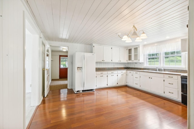 kitchen featuring sink, an inviting chandelier, white refrigerator with ice dispenser, wood-type flooring, and white cabinets