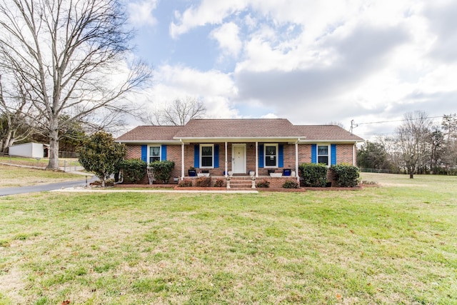 ranch-style home featuring covered porch and a front lawn