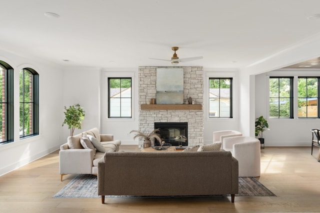 living room with ceiling fan, light hardwood / wood-style flooring, crown molding, and a fireplace