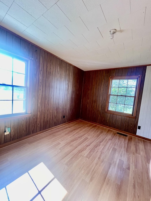 spare room with light hardwood / wood-style flooring and wood walls