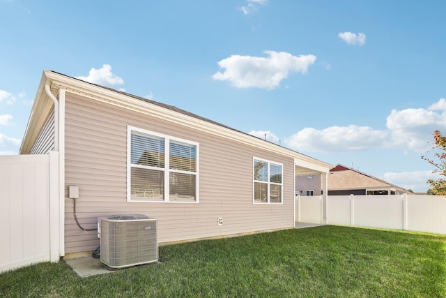 back of property featuring a yard and central AC