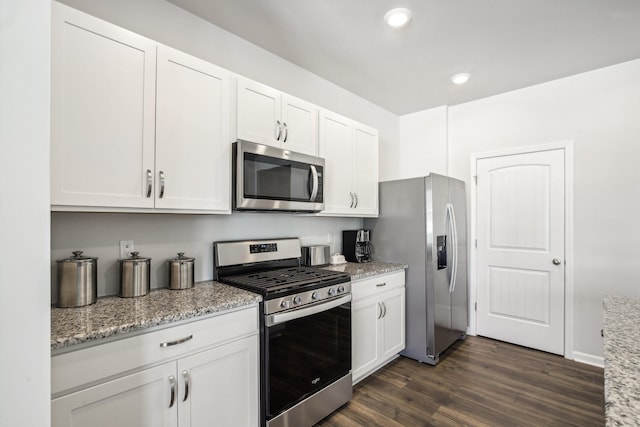 kitchen featuring light stone countertops, white cabinetry, stainless steel appliances, and dark wood-type flooring