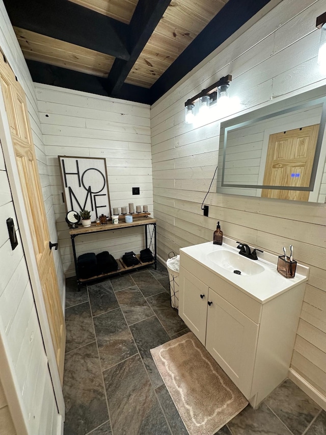 bathroom with beamed ceiling, vanity, wooden ceiling, and wooden walls