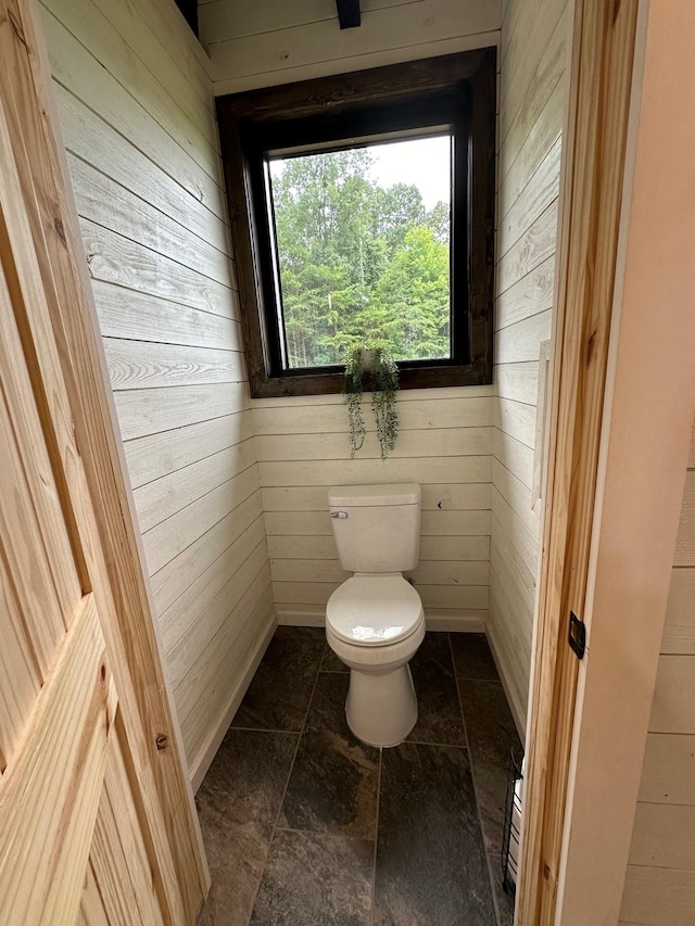 bathroom featuring toilet and wooden walls