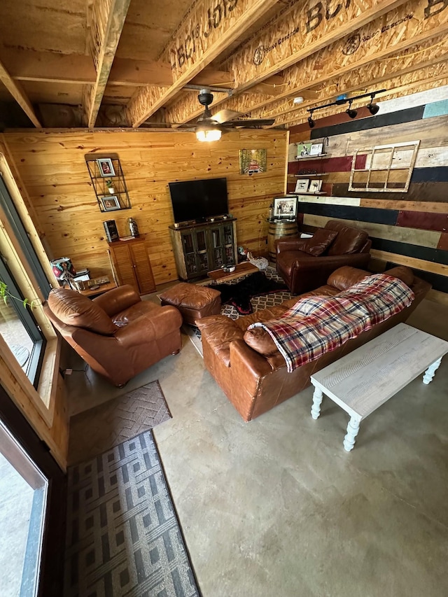 living room with beam ceiling, ceiling fan, wood walls, concrete flooring, and wood ceiling