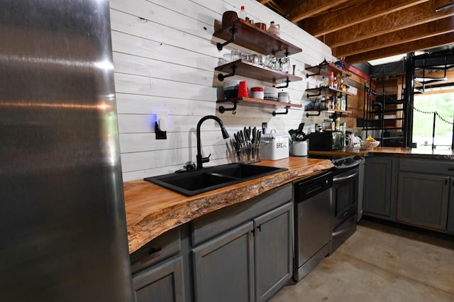 kitchen featuring wood walls, sink, stainless steel dishwasher, gray cabinets, and butcher block counters