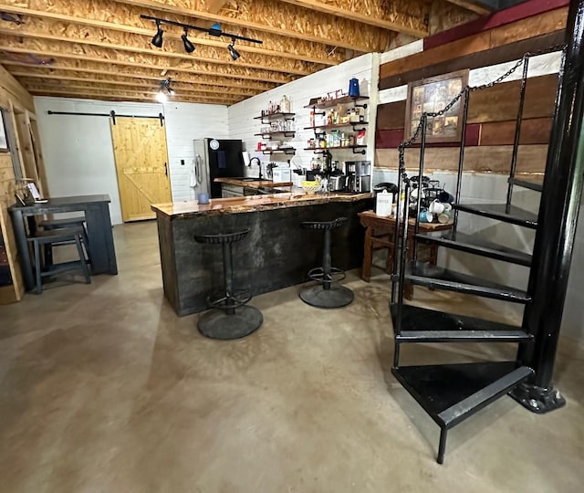 bar featuring a barn door, black fridge, and concrete floors