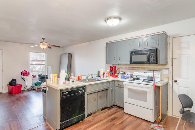 kitchen featuring kitchen peninsula, gray cabinetry, sink, black appliances, and hardwood / wood-style floors