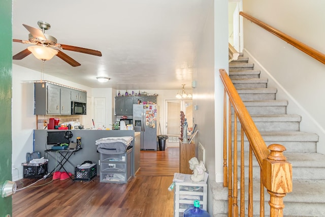 interior space featuring ceiling fan with notable chandelier and dark hardwood / wood-style floors