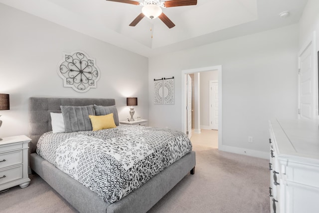 bedroom with a raised ceiling, ceiling fan, and light carpet