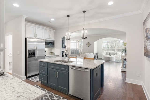 kitchen featuring appliances with stainless steel finishes, a kitchen island with sink, sink, decorative light fixtures, and white cabinetry