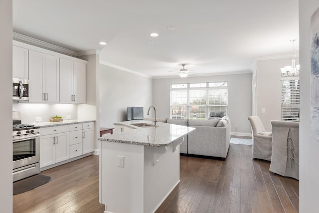 kitchen featuring appliances with stainless steel finishes, light stone counters, sink, a center island with sink, and white cabinets