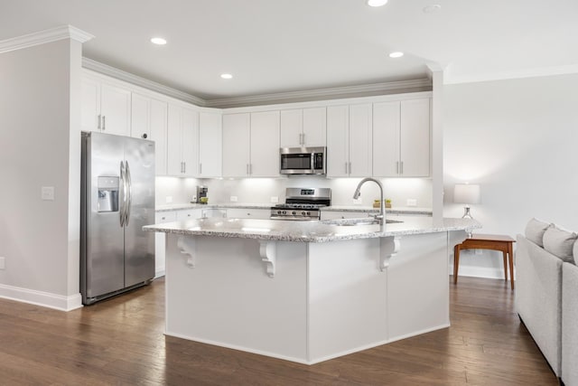 kitchen featuring a breakfast bar area, a center island with sink, white cabinets, and appliances with stainless steel finishes