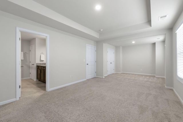 carpeted spare room with a raised ceiling