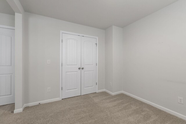 unfurnished bedroom featuring light colored carpet and a closet