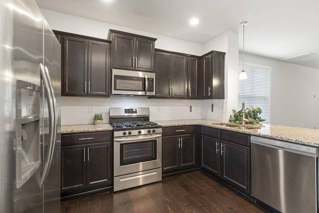 kitchen with backsplash, dark wood-type flooring, sink, hanging light fixtures, and appliances with stainless steel finishes