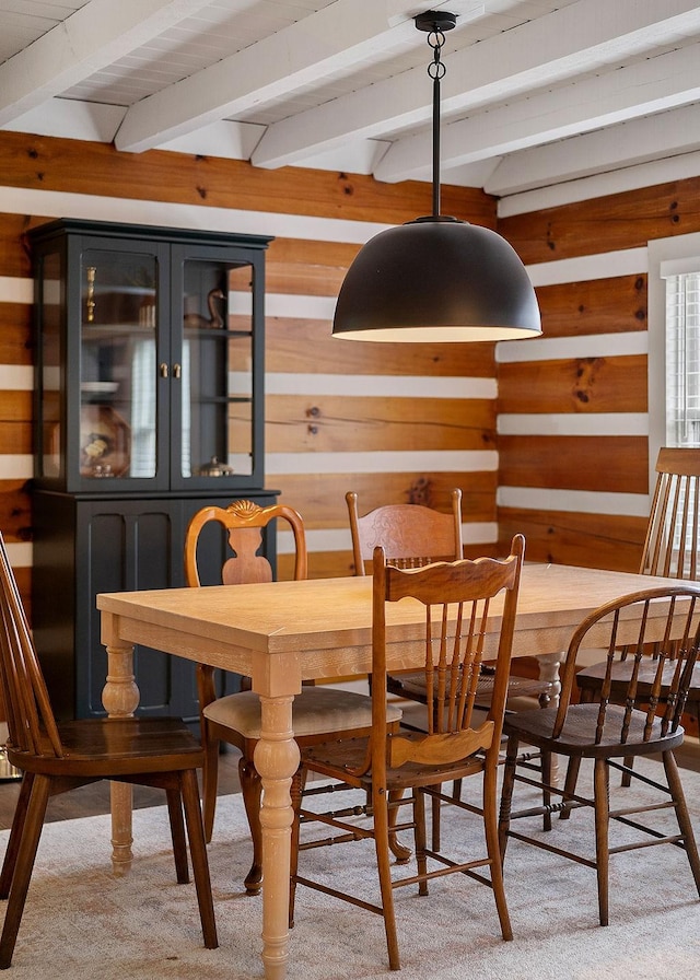 carpeted dining room featuring beamed ceiling