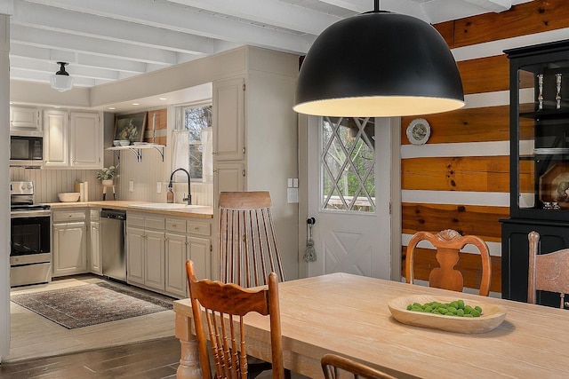 dining room featuring beamed ceiling, hardwood / wood-style flooring, a wealth of natural light, and sink