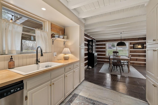 kitchen featuring white cabinetry, dishwasher, sink, beamed ceiling, and pendant lighting