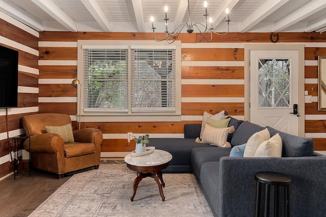 living room with wooden walls, beamed ceiling, a chandelier, and wood-type flooring