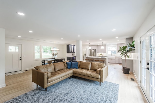 living room with light hardwood / wood-style flooring, a notable chandelier, and sink