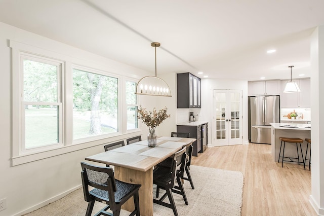 dining area with plenty of natural light, french doors, and light wood-type flooring