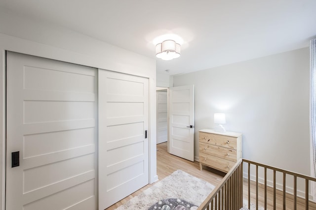 unfurnished bedroom featuring a closet, a nursery area, and light wood-type flooring