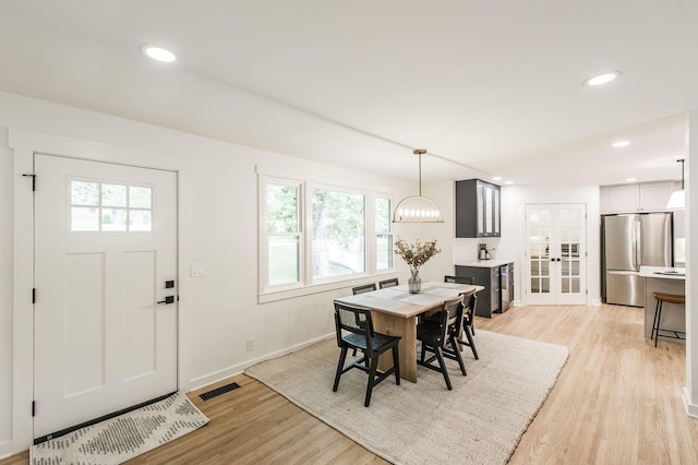 dining area featuring a chandelier, french doors, and light hardwood / wood-style floors