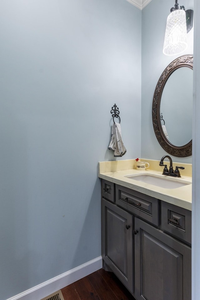 bathroom featuring wood-type flooring, vanity, and ornamental molding