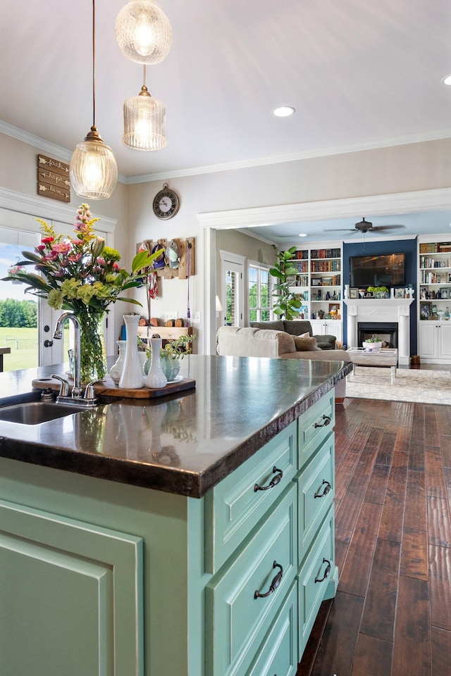 kitchen with a center island, sink, green cabinetry, ceiling fan, and decorative light fixtures