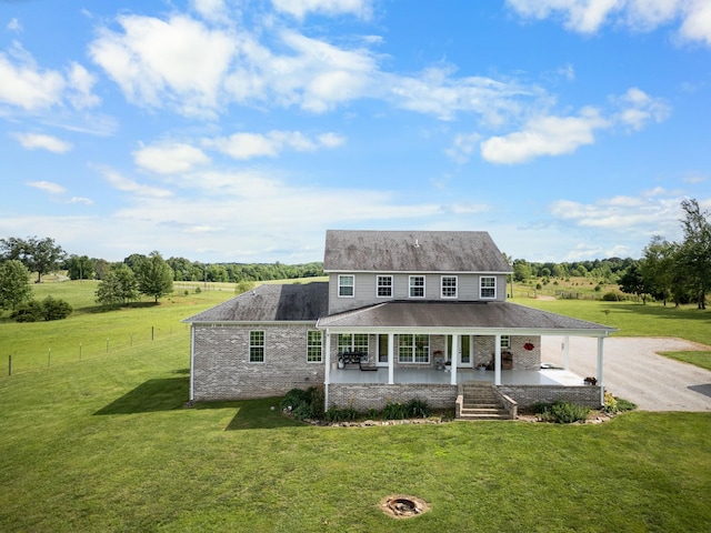 farmhouse inspired home featuring a rural view, covered porch, and a front yard