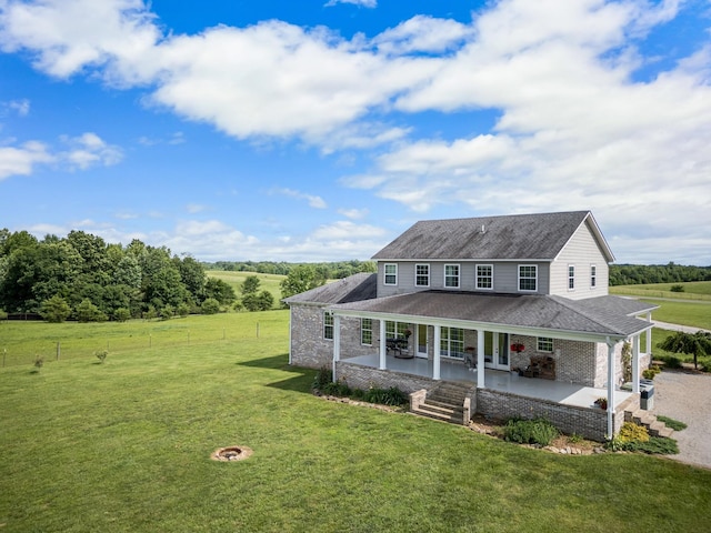 country-style home with a front lawn, a patio, a rural view, and an outdoor fire pit