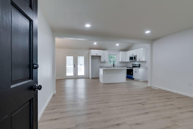 kitchen featuring french doors, light hardwood / wood-style flooring, appliances with stainless steel finishes, a kitchen island, and white cabinetry