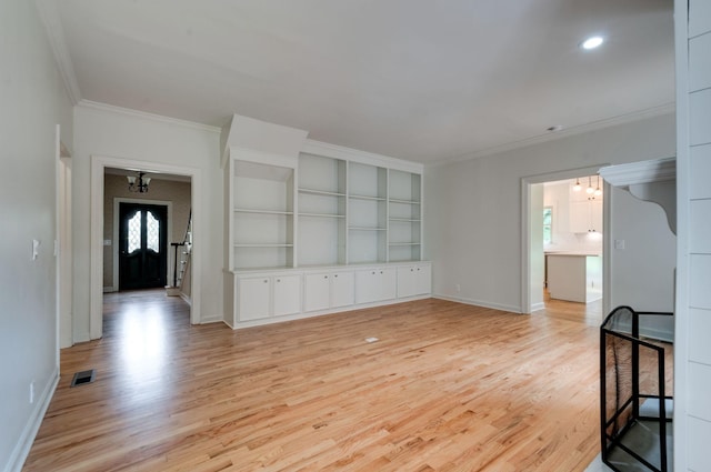 unfurnished living room featuring built in shelves, light hardwood / wood-style floors, and crown molding