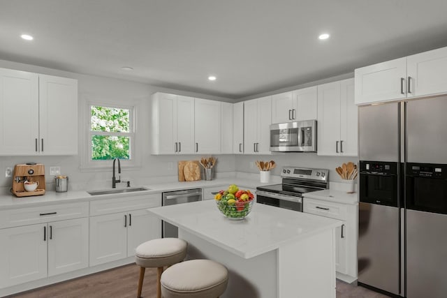 kitchen featuring a kitchen bar, appliances with stainless steel finishes, sink, white cabinets, and a kitchen island