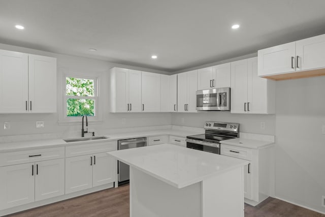 kitchen with white cabinetry, sink, stainless steel appliances, dark hardwood / wood-style flooring, and a kitchen island