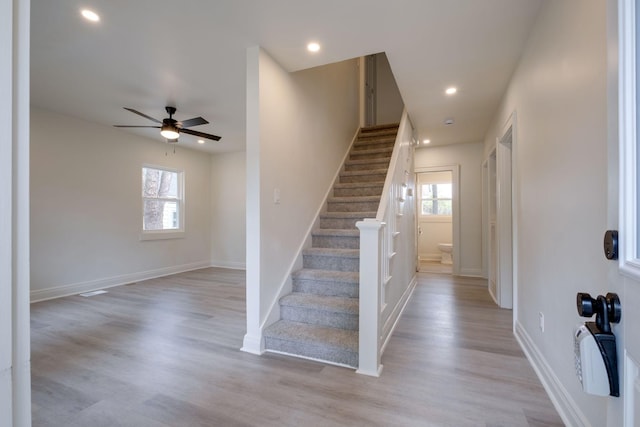 stairs with hardwood / wood-style flooring and ceiling fan