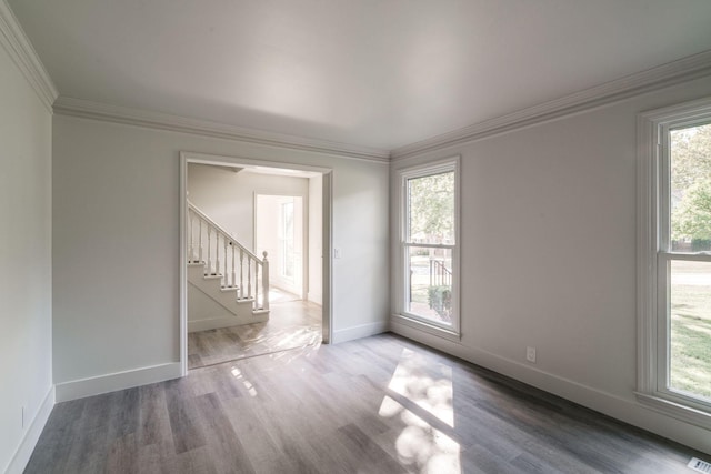 empty room featuring a healthy amount of sunlight, ornamental molding, and wood-type flooring