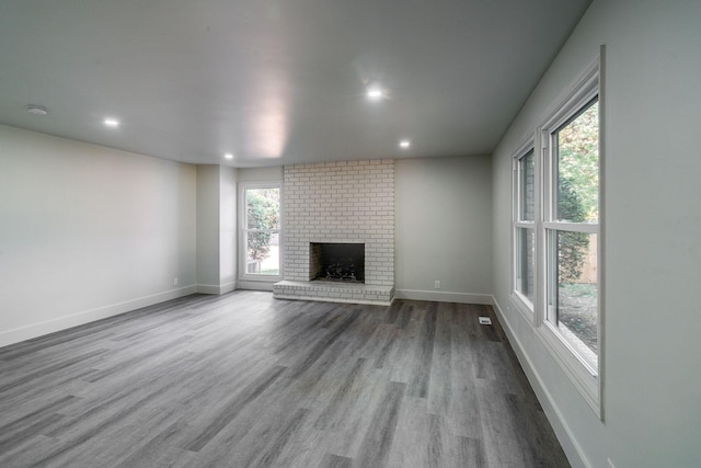 unfurnished living room featuring light wood-type flooring and a brick fireplace