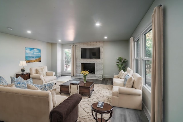 living room with wood-type flooring and a brick fireplace