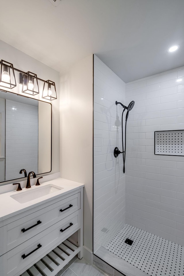 bathroom with a tile shower and vanity