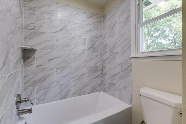 bathroom featuring toilet, a healthy amount of sunlight, and tiled shower / bath