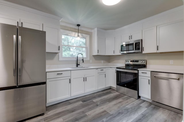 kitchen featuring white cabinets, decorative light fixtures, sink, and appliances with stainless steel finishes