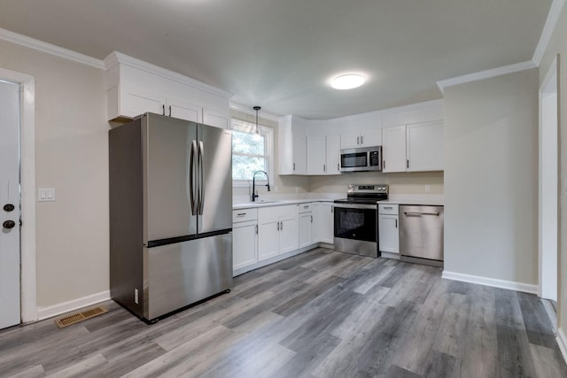 kitchen with crown molding, sink, hanging light fixtures, white cabinetry, and stainless steel appliances